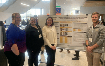 Doctor of Physical Therapy students stand with poster board displaying research