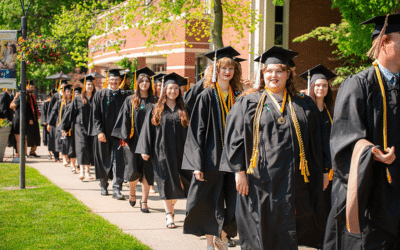 Graduates lined up walking down a sidewalk for the class of 2024