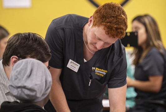 Male nursing student in scrubs talks to two people
