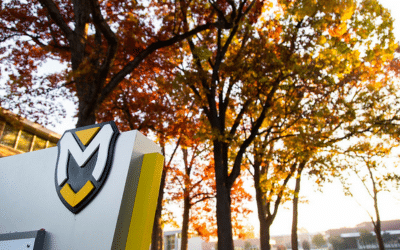 Manchester University signage in front of autumn trees