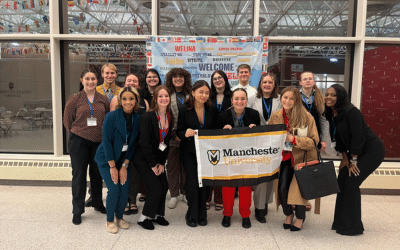 Group of students hold a Manchester University flag
