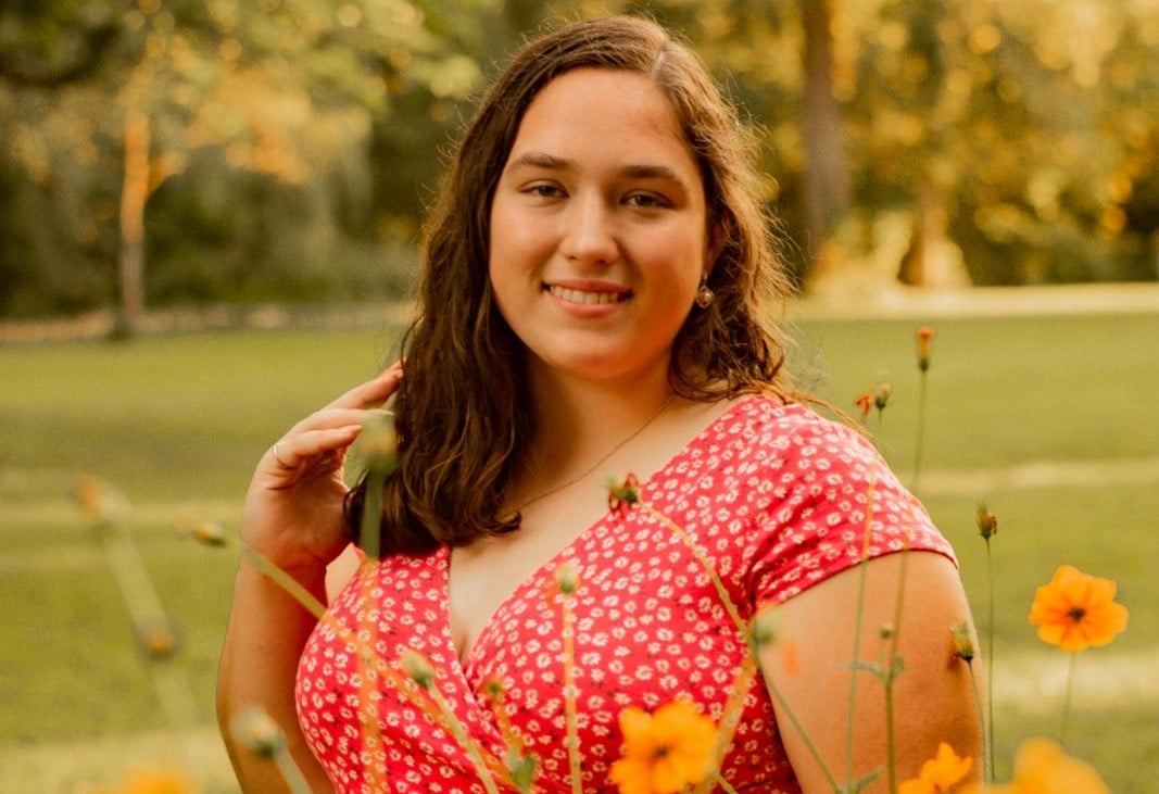 Student poses outside with flowers