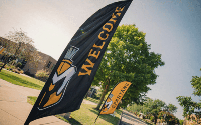 Black and gold feather flags saying "Welcome Spartans" placed outside on campus