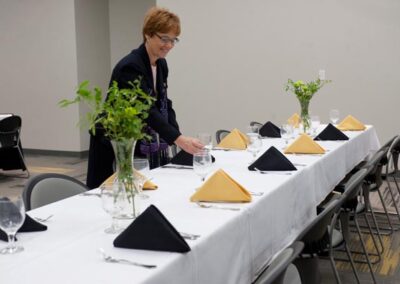 Woman sets a table with black and gold napkins