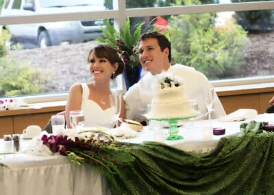 Bride and groom smile with cake at a wedding reception
